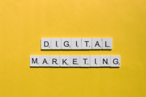 Imagem com as palavras 'DIGITAL MARKETING' formadas por letras brancas sobre um fundo amarelo, representando conceitos de marketing digital.